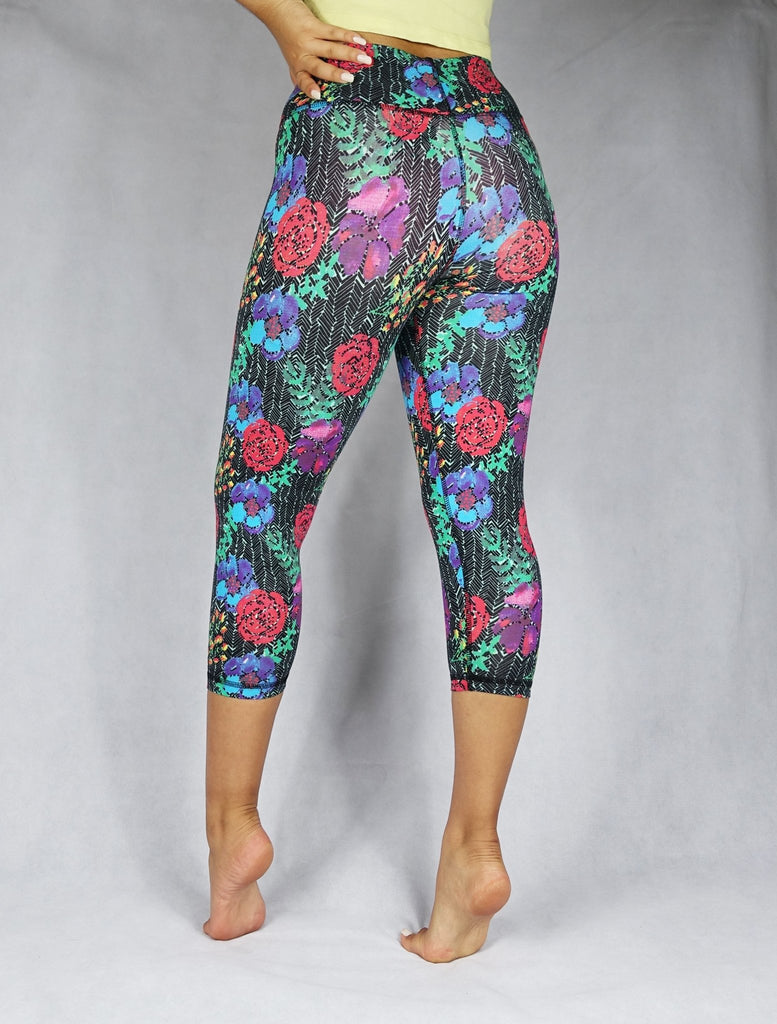 Back view of a model wearing crop legging of red, blue and green flowery prints