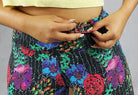 Close up view of red, blue and green flowery print full length leggings with a pocket inside the waistband for keys and cards
