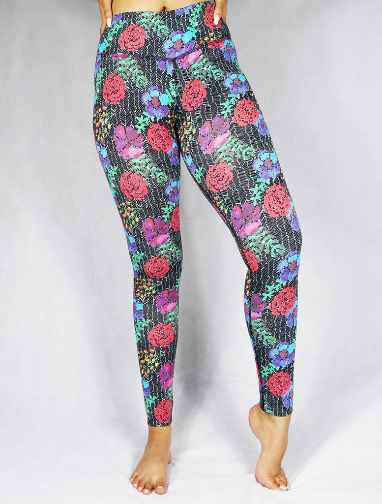Front view of a model wearing full length legging with a red, blue and green flowery prints 