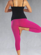 Back view of model in a yoga pose wearing pink crop leggings
